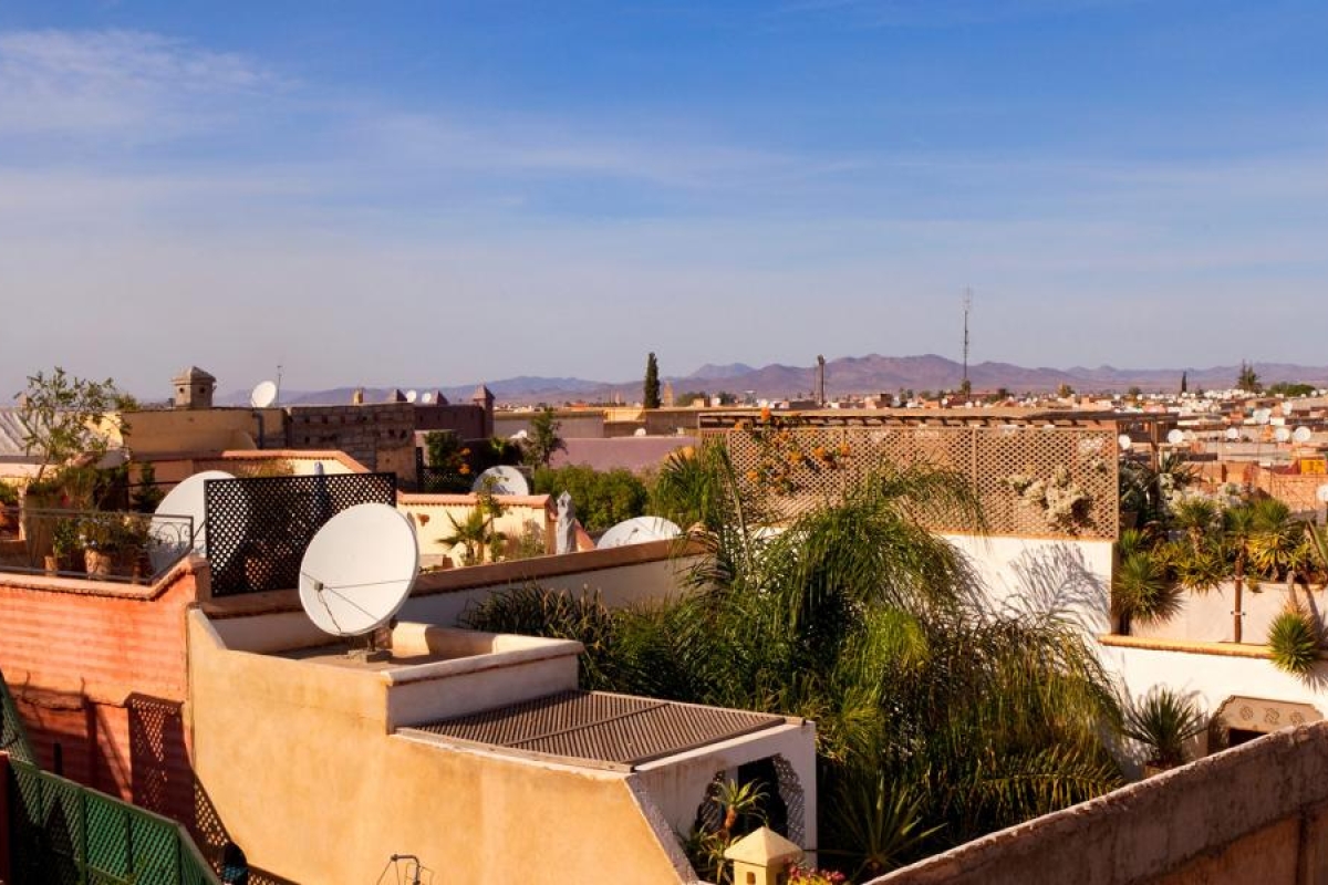 Image of rooftops with satellite dishes in a sunlit cityscape.