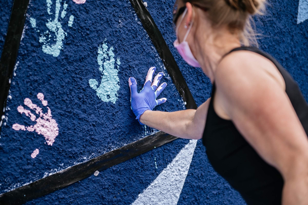 person painting with hands on mural