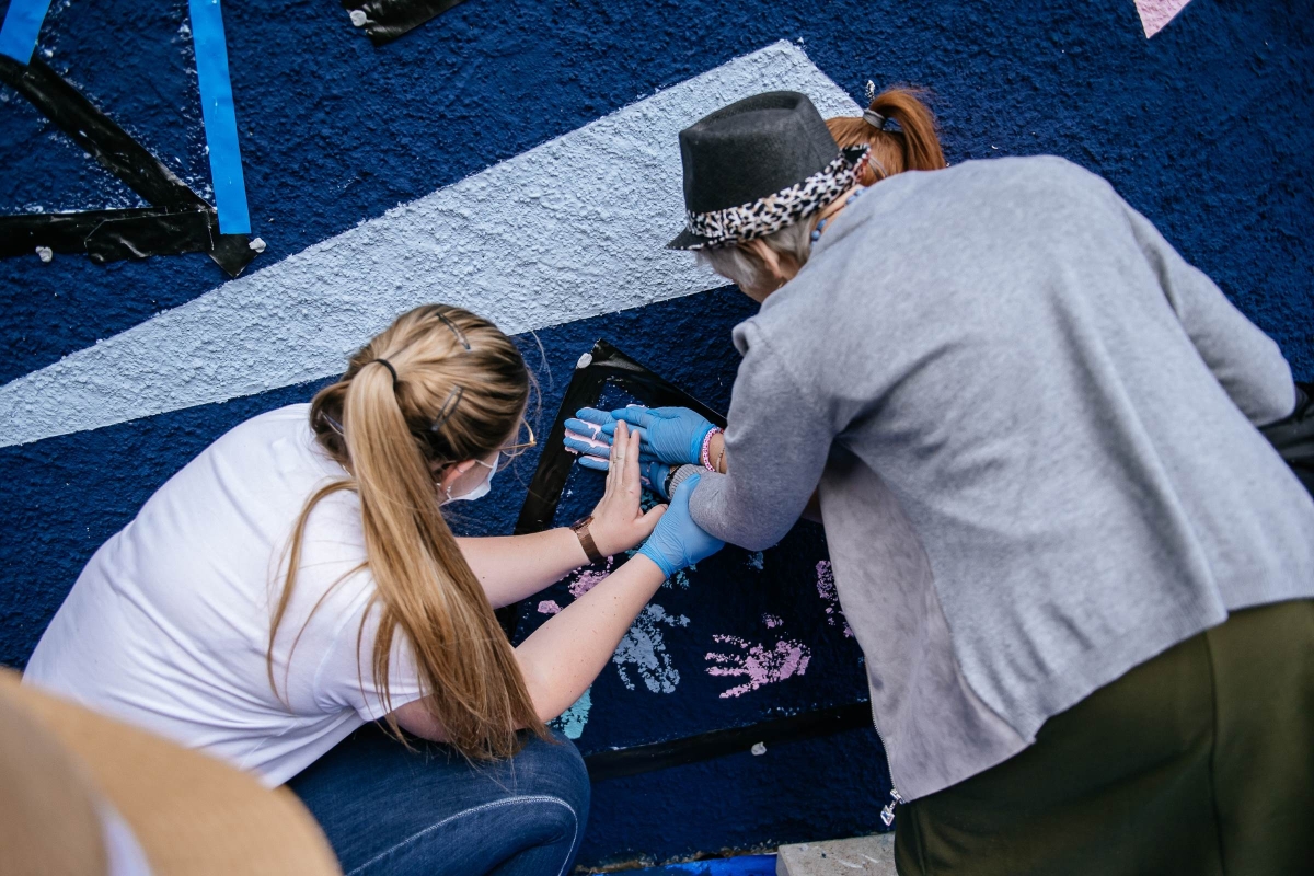 people painting hands on mural