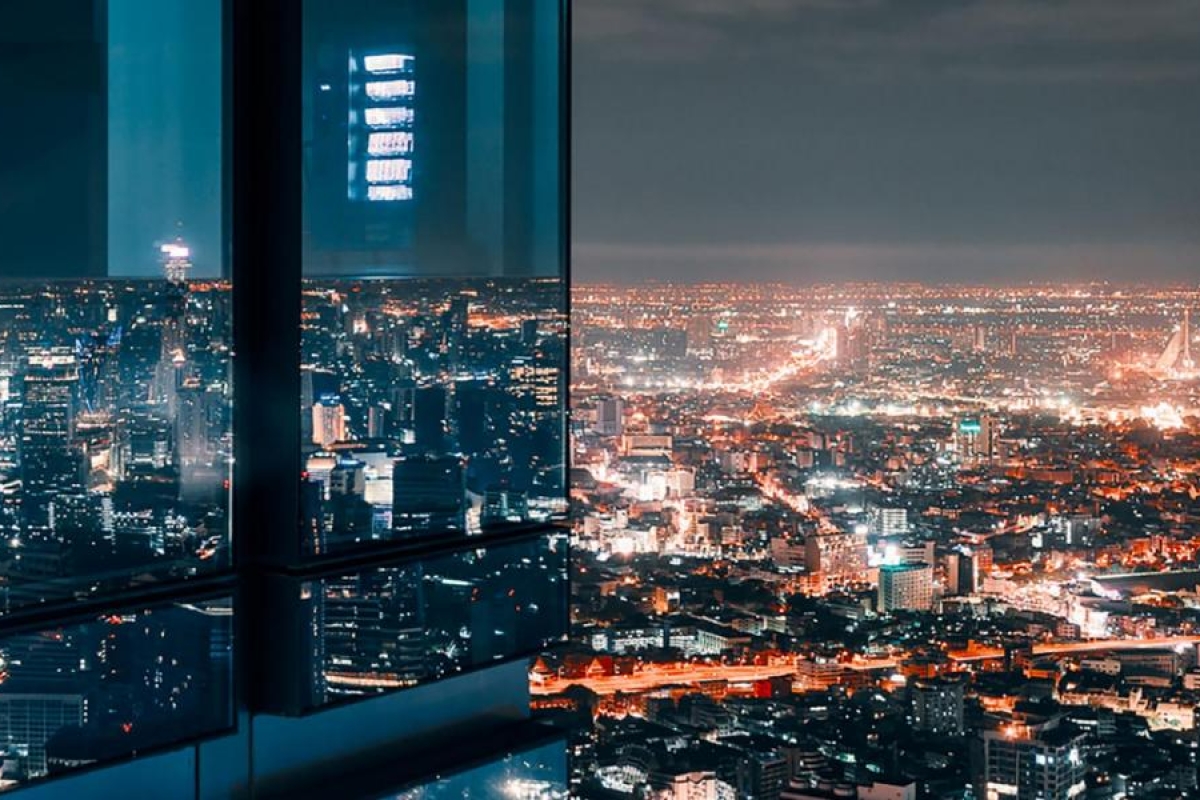 Image of nighttime cityscape with illuminated buildings and reflections in a glass window