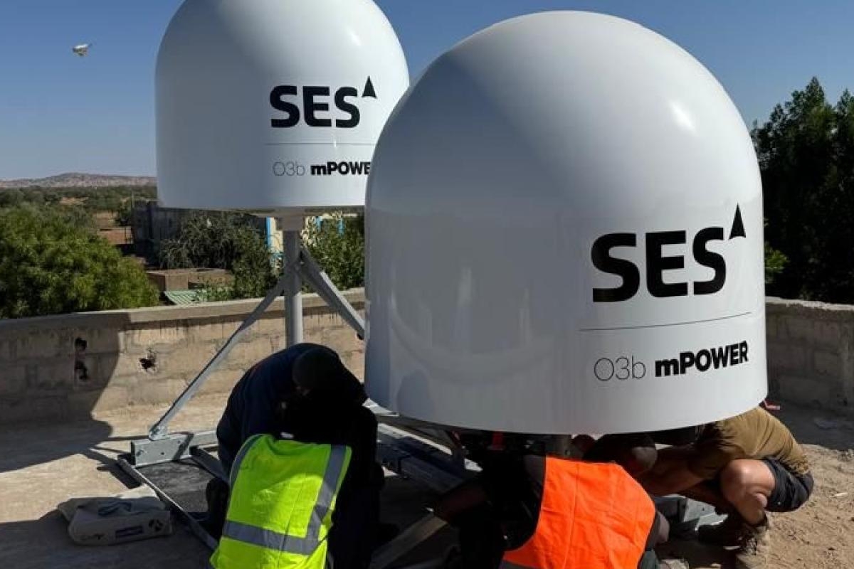 Technicians installing SES satellite equipment on a rooftop.