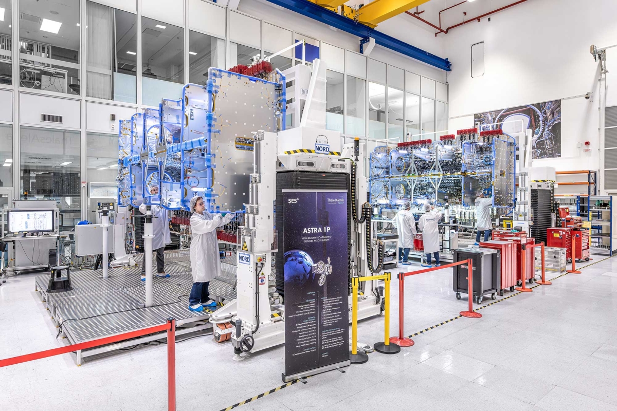 Technicians assembling satellite hardware in a cleanroom facility.”