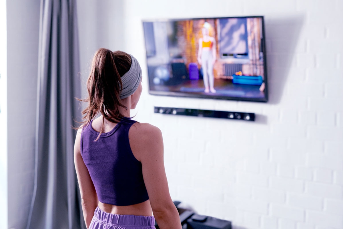 Person following an exercise video on a TV at home.