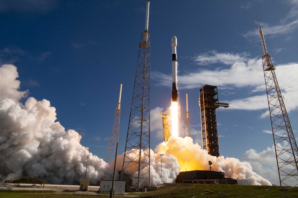 Rocket launching from the pad with smoke and flames rising.