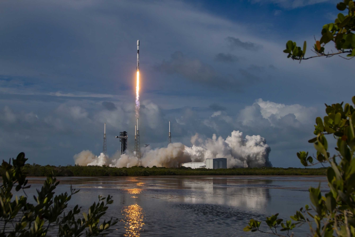 Landscape image of Rocket launching from the pad with smoke and flames rising.