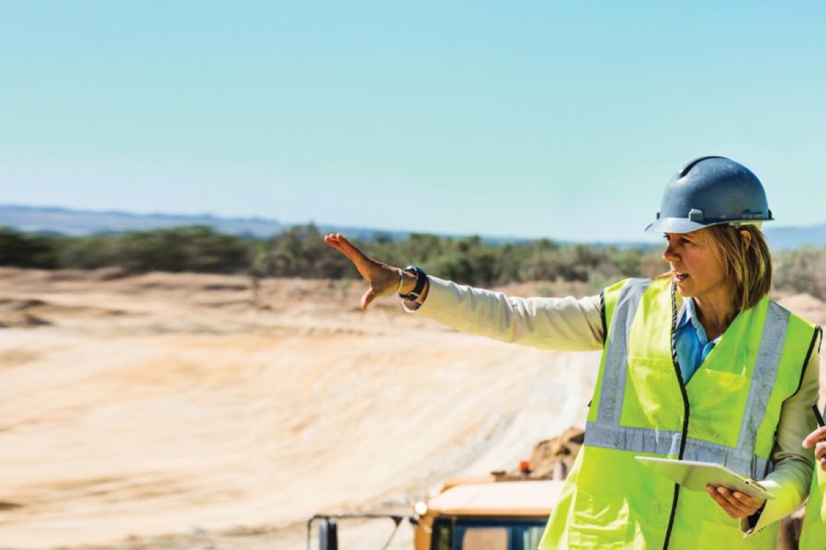 Image of three workers discussing construction plans outdoors.