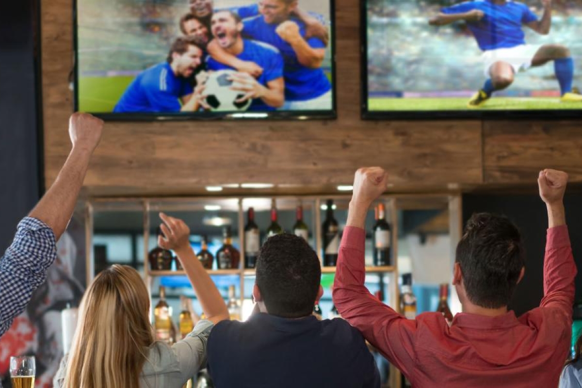 Image of a group of friends enjoying a sports game at a bar.