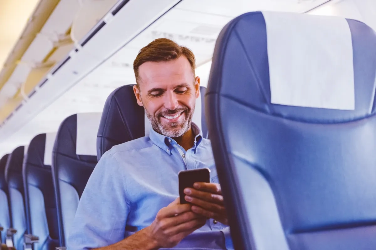 Image of a person using mobile phone inside an airplane
