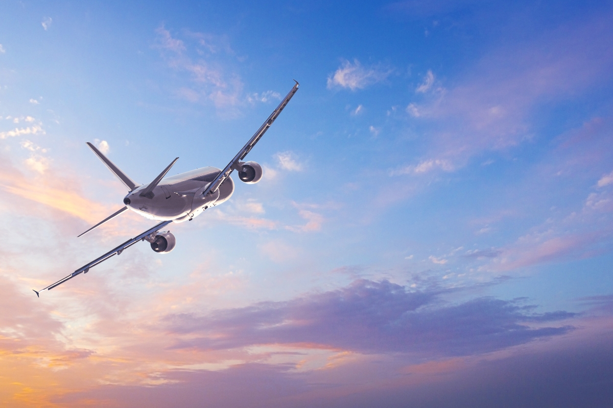 Image of an airplane with a sunset colours and clouds in the background