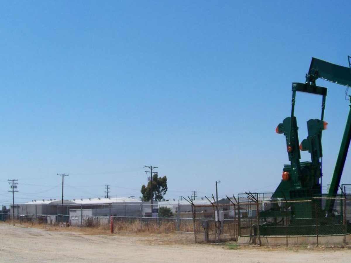 Image of oil pumpjacks operating in a fenced field.