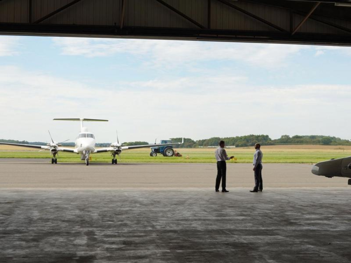 Image of a plane in an aerodrome and two people next to it.