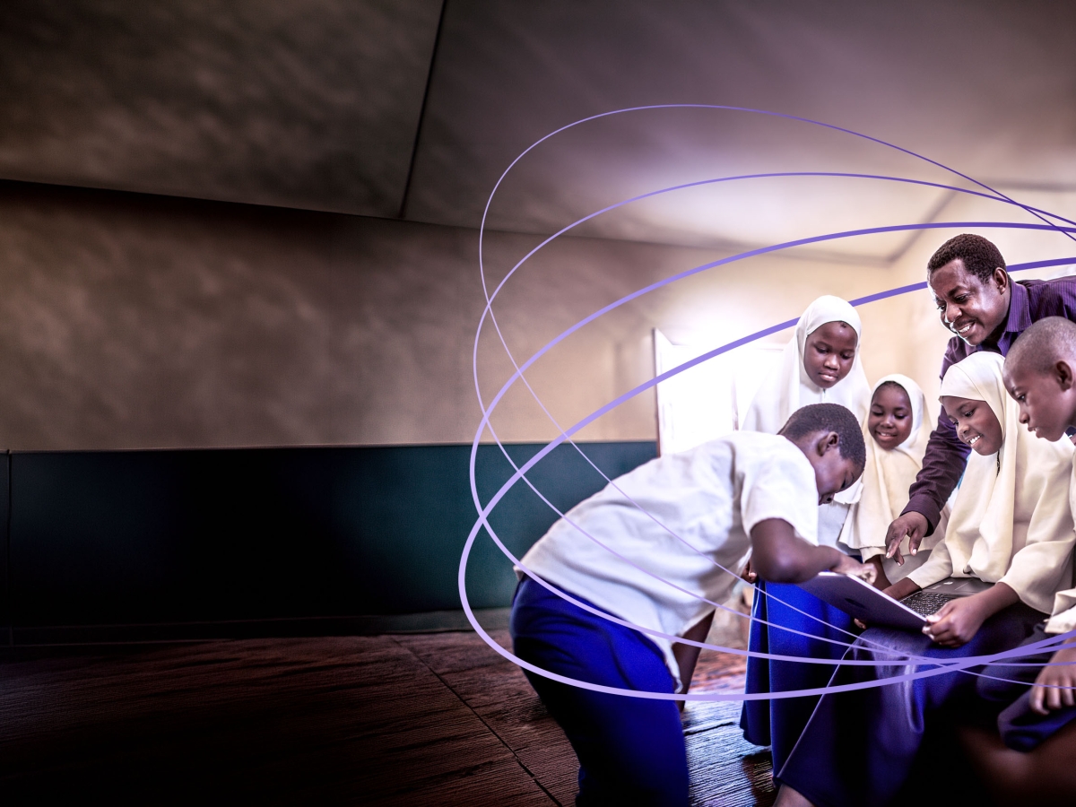 students and teacher looking at laptop