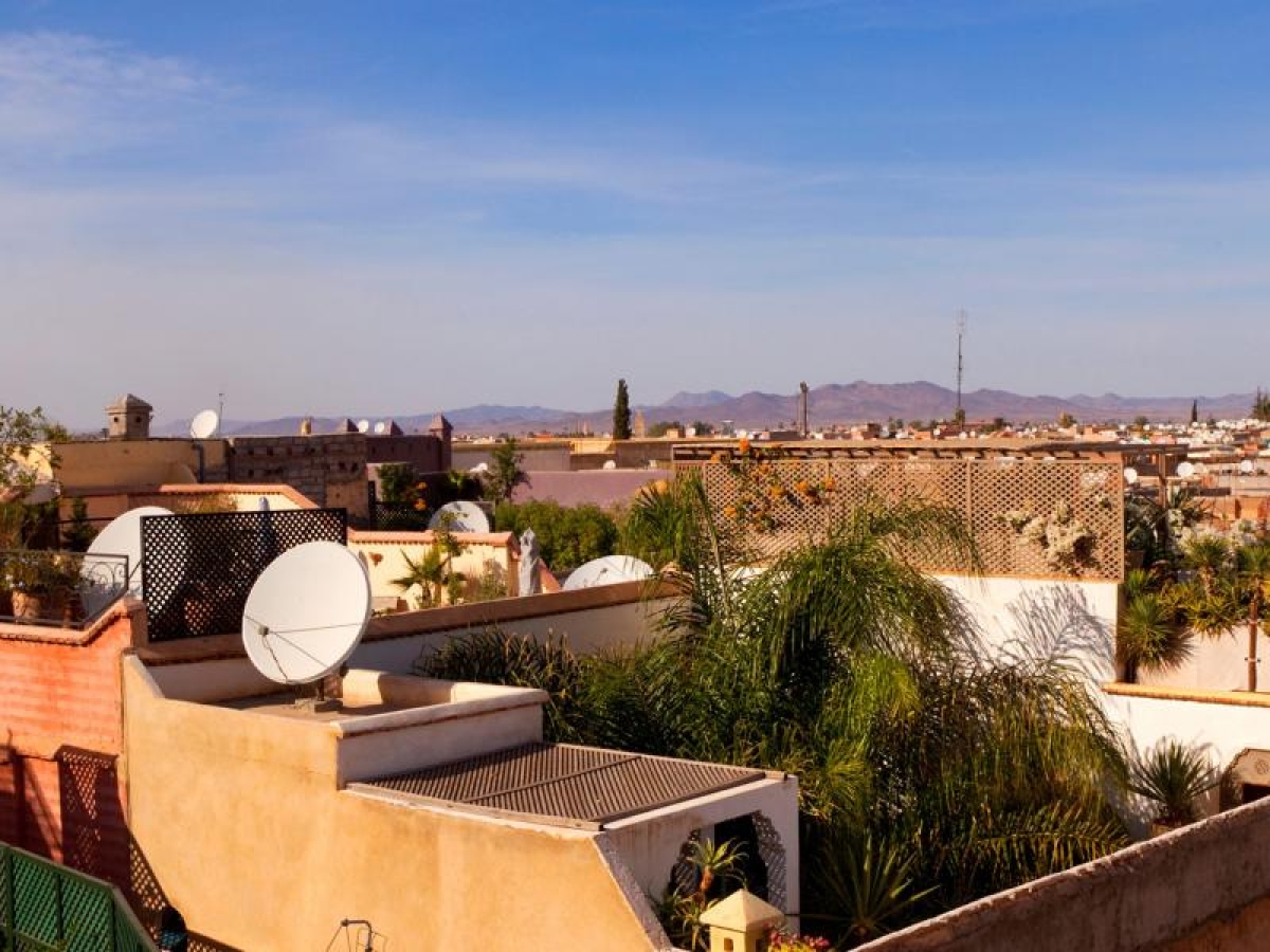 Image of rooftops with satellite dishes in a sunlit cityscape.
