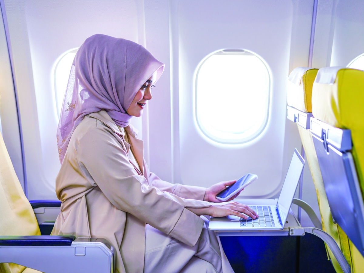 woman using laptop and cellphone on flight