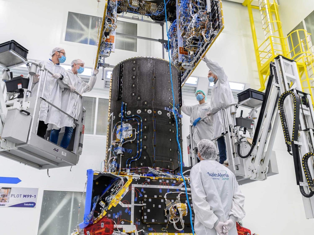 Technicians working on satellite modules in a cleanroom.
