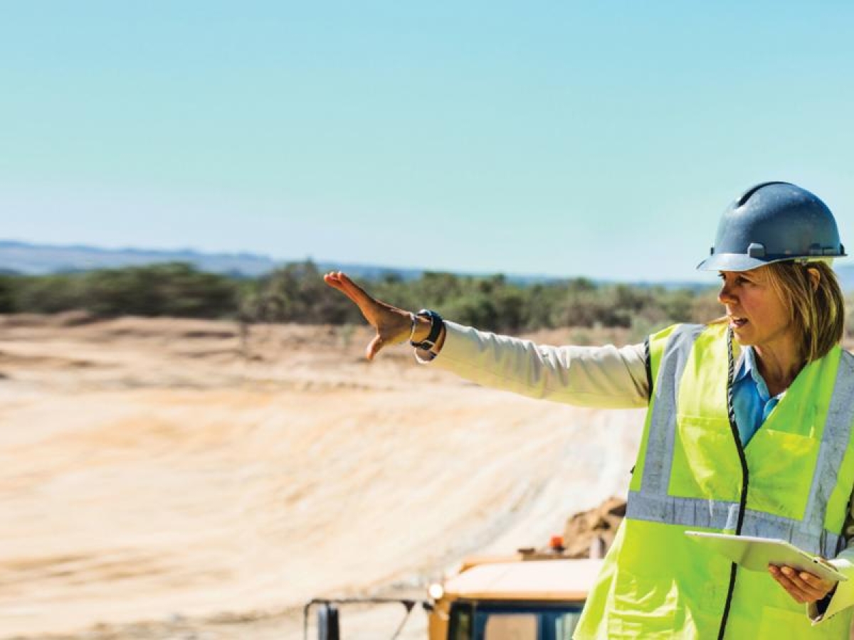 Image of three workers discussing construction plans outdoors.