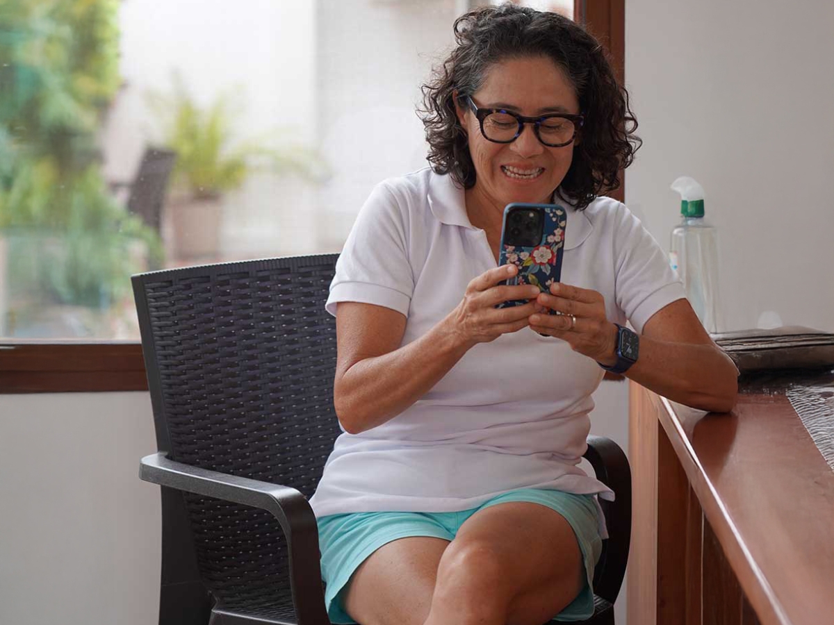 Image of Dalila Castillo sitting on a chair using a mobilephone.