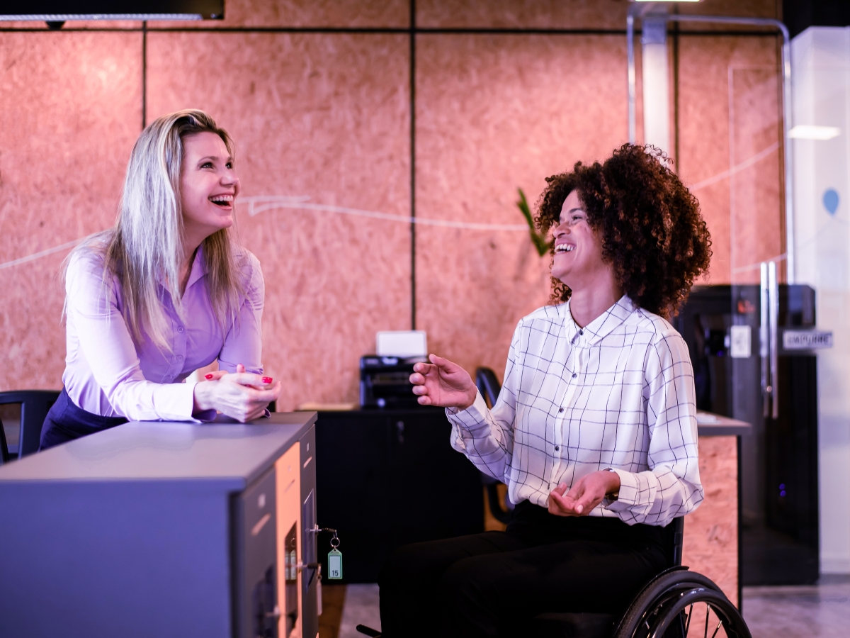 Two colleagues laughing and chatting together in an office.