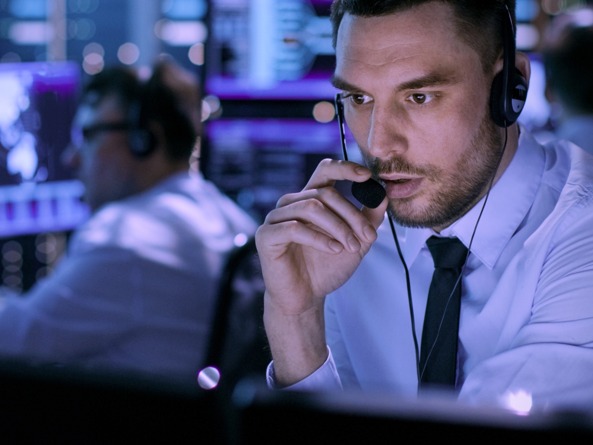 Person working in a control room with multiple data screens.