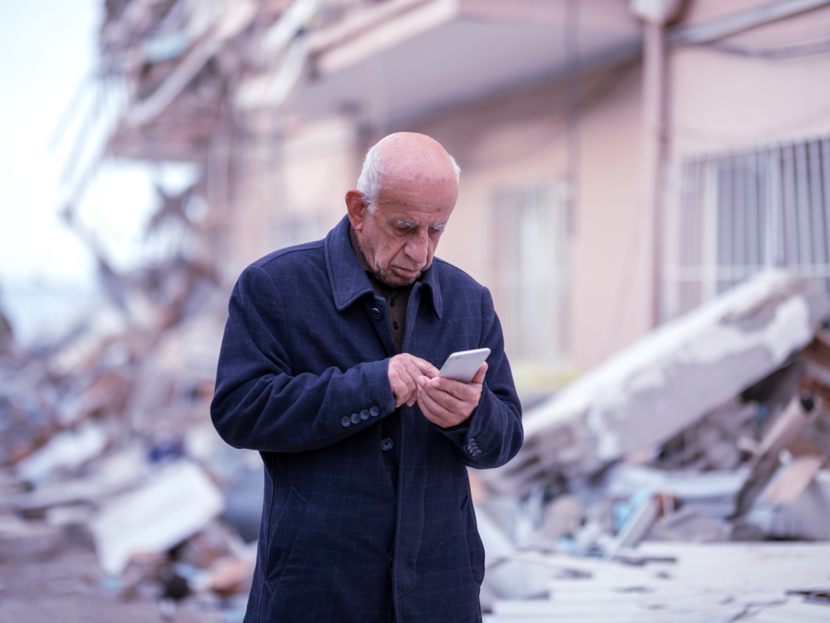 Person using a smartphone in a disaster-affected area.
