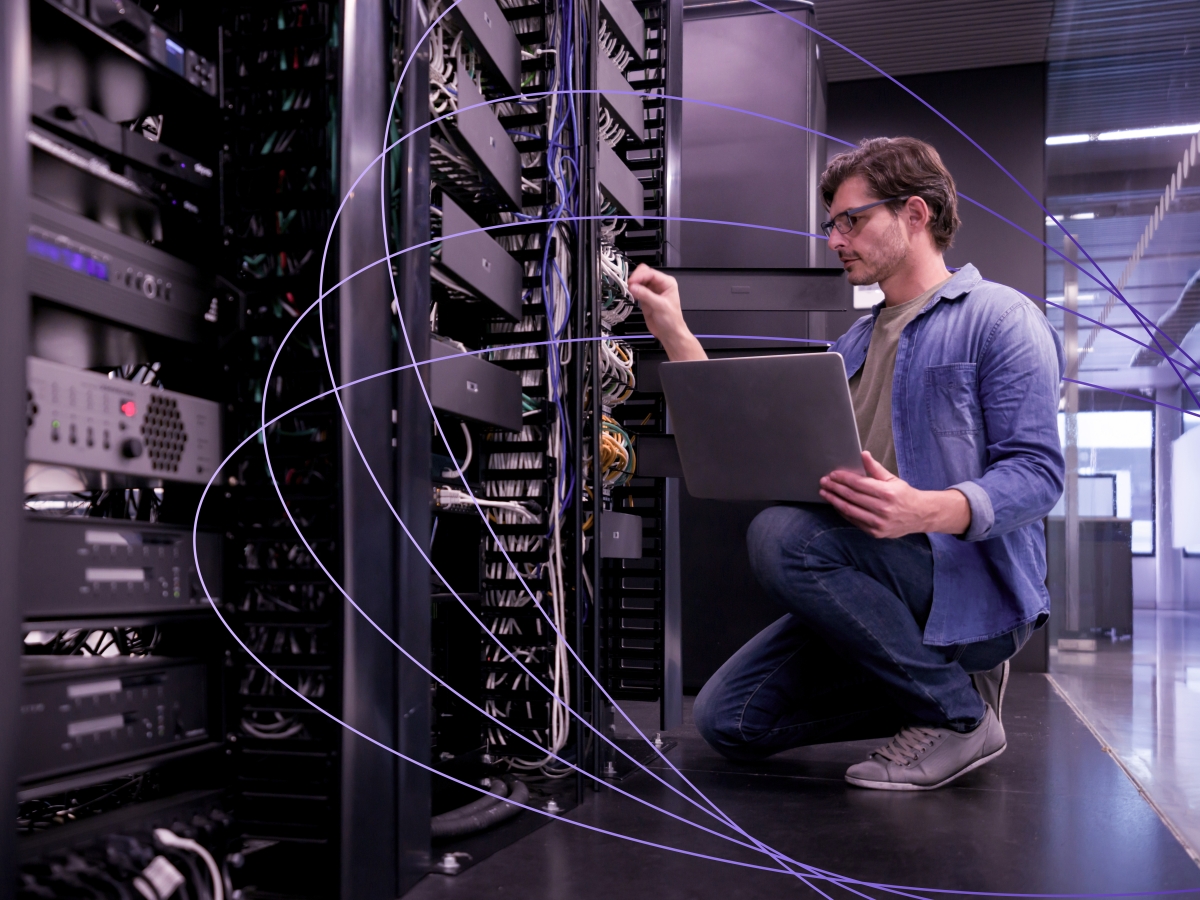 Image of a person using a laptop while working on network servers
