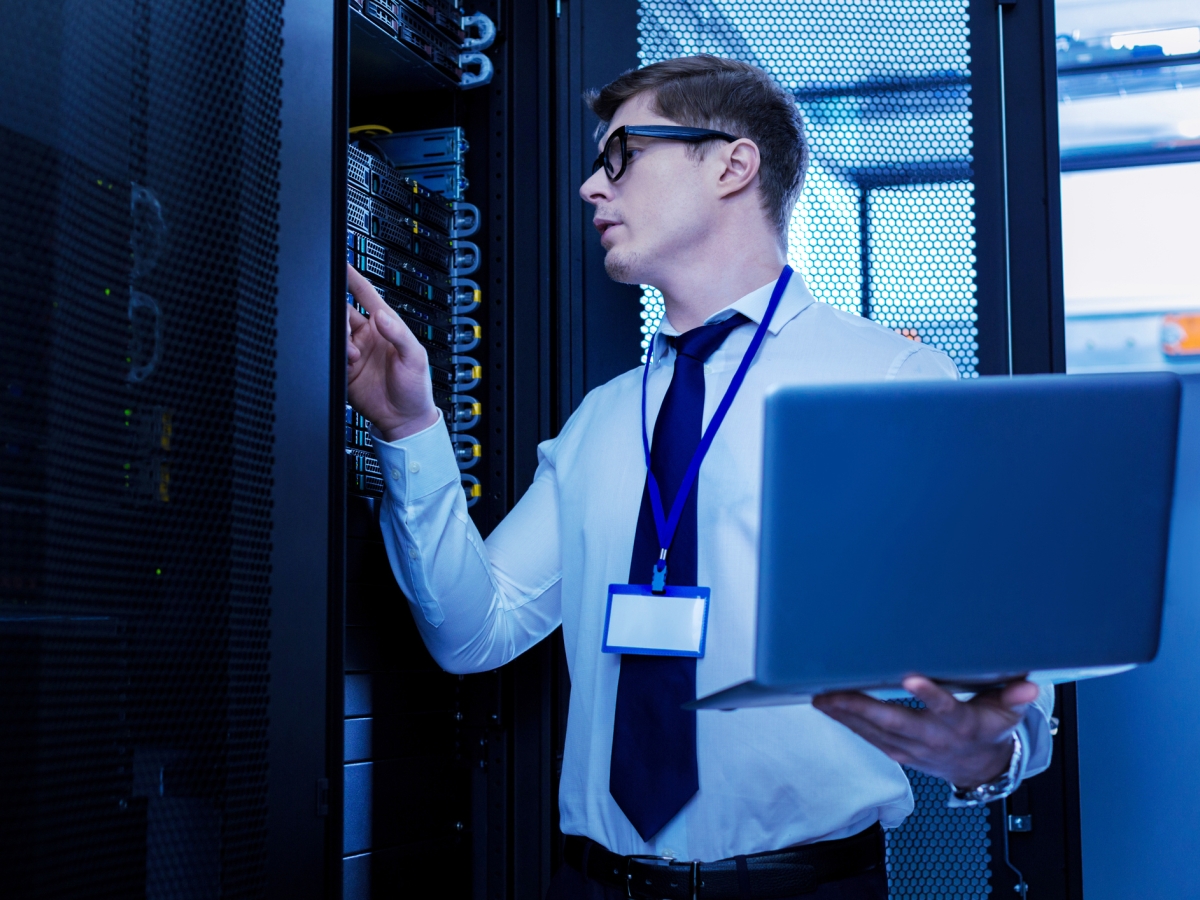 Image of a person using a laptop and working with servers