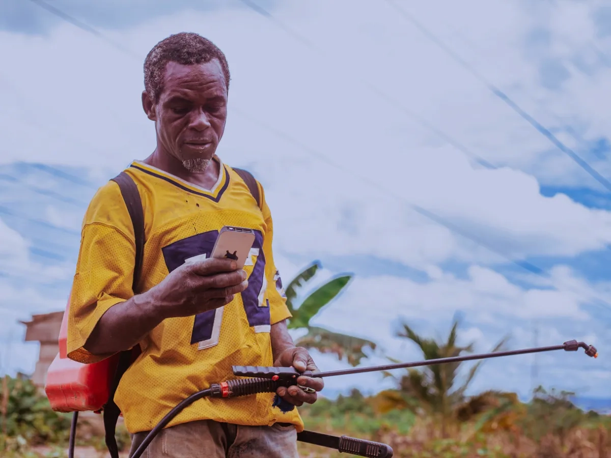 Image of an agricultural worker checking smartphone outdoors.