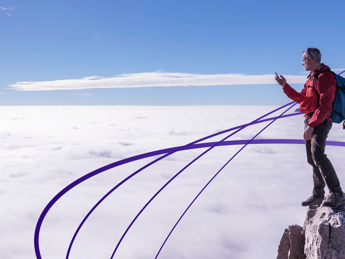 Image of a person using a phone on a rocky mountaintop.