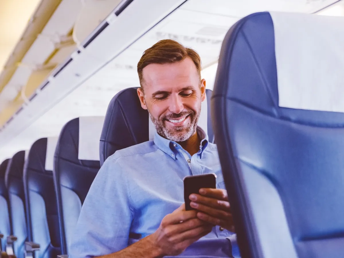 Image of a person using mobile phone inside an airplane
