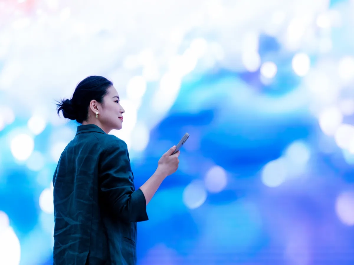 Person holding a smartphone in front of an immersive digital visualization.